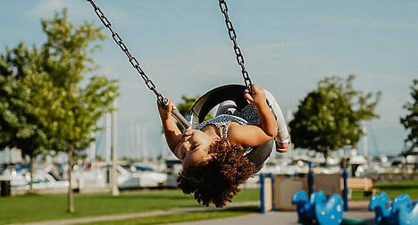 Child playing on a swing in a park. Materials from recycled electricals can be remanufactured into children's playground equipment.