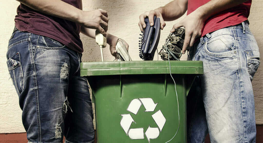 A photo of electrical items being placed into a recycling bin