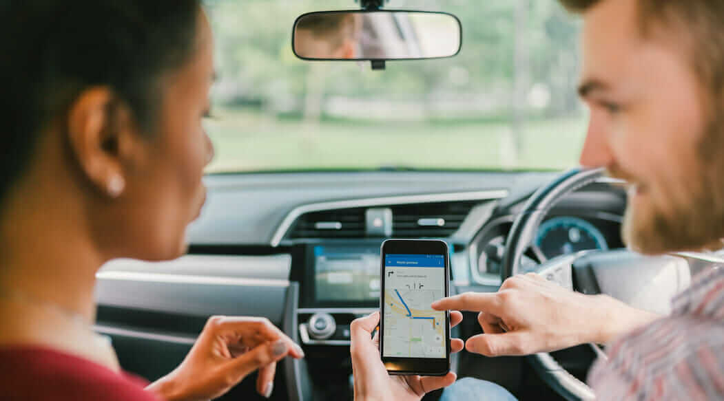 Woman and man in a car using gps on a smart device
