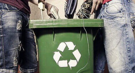 people putting items in a recycling bin