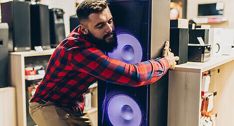 man hugging speaker in store