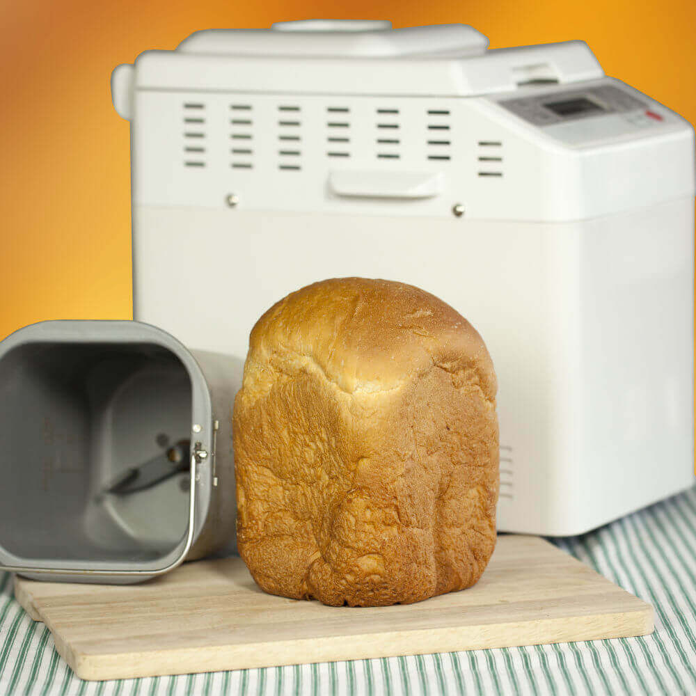 Breadmaker with a fresh loaf in front of it