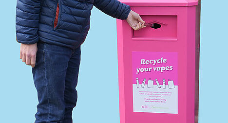 Man putting a vape in to a pink recycling bin