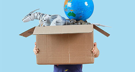 a child holding a large box of toys and the box covers their face entirely