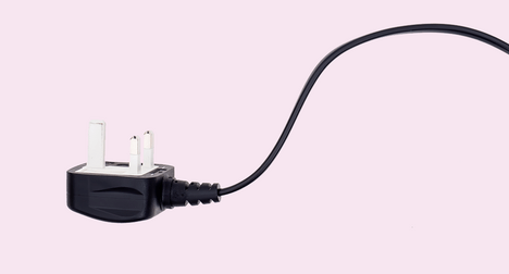 a black 3 pin plug and its cable on a plain pink background