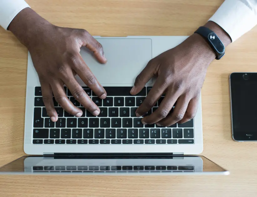 overhead shot of a dark skinned man using a modern laptop