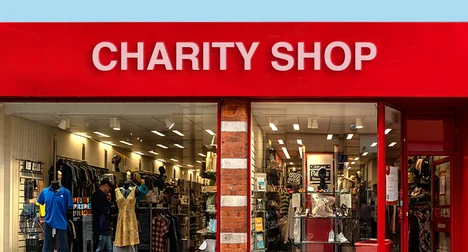 Shop front window of a red shop with a 'Charity Shop' sign.