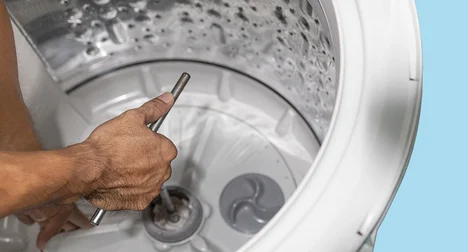 Washing machine drum being repaired, close up on the drum and hand.