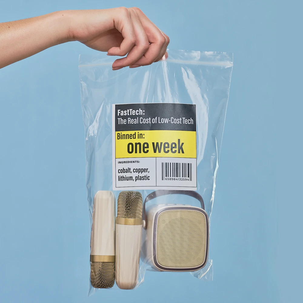 a pale skinned hand holdin a clear plastic bag with two small microphones and a speaker. The label on the bag says "one week"
